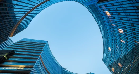 Modern curved glass skyscraper facades reflecting clear blue sky at night - stock photo