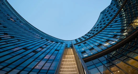 Illuminated modern curved skyscrapers against clear blue sky at dusk - stock photo